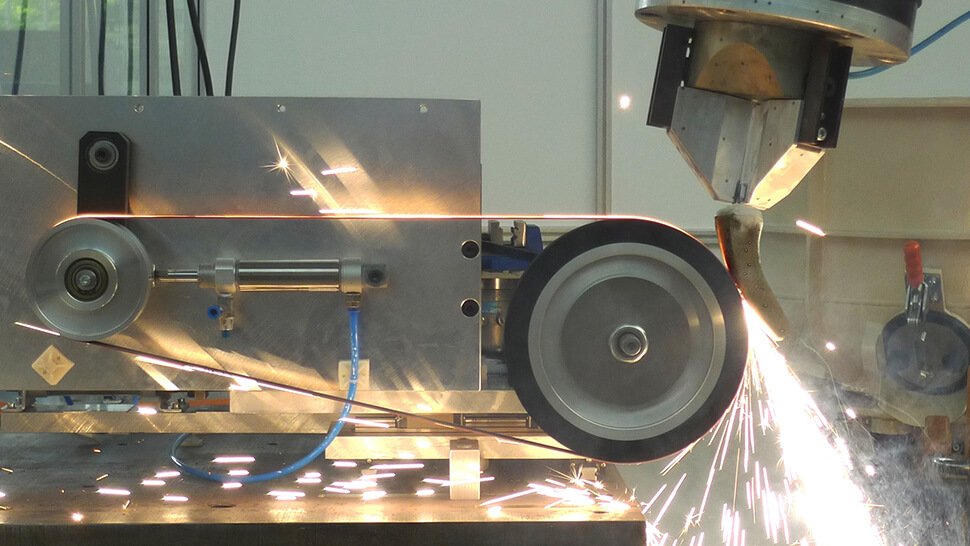 Roboterbearbeitung: die Bearbeitung einer Turbinenschaufel mittels Schleifband, wobei die Turbinenschaufel kraftgeregelt vom Roboter an das Schleifband geführt wird. Foto: IWF